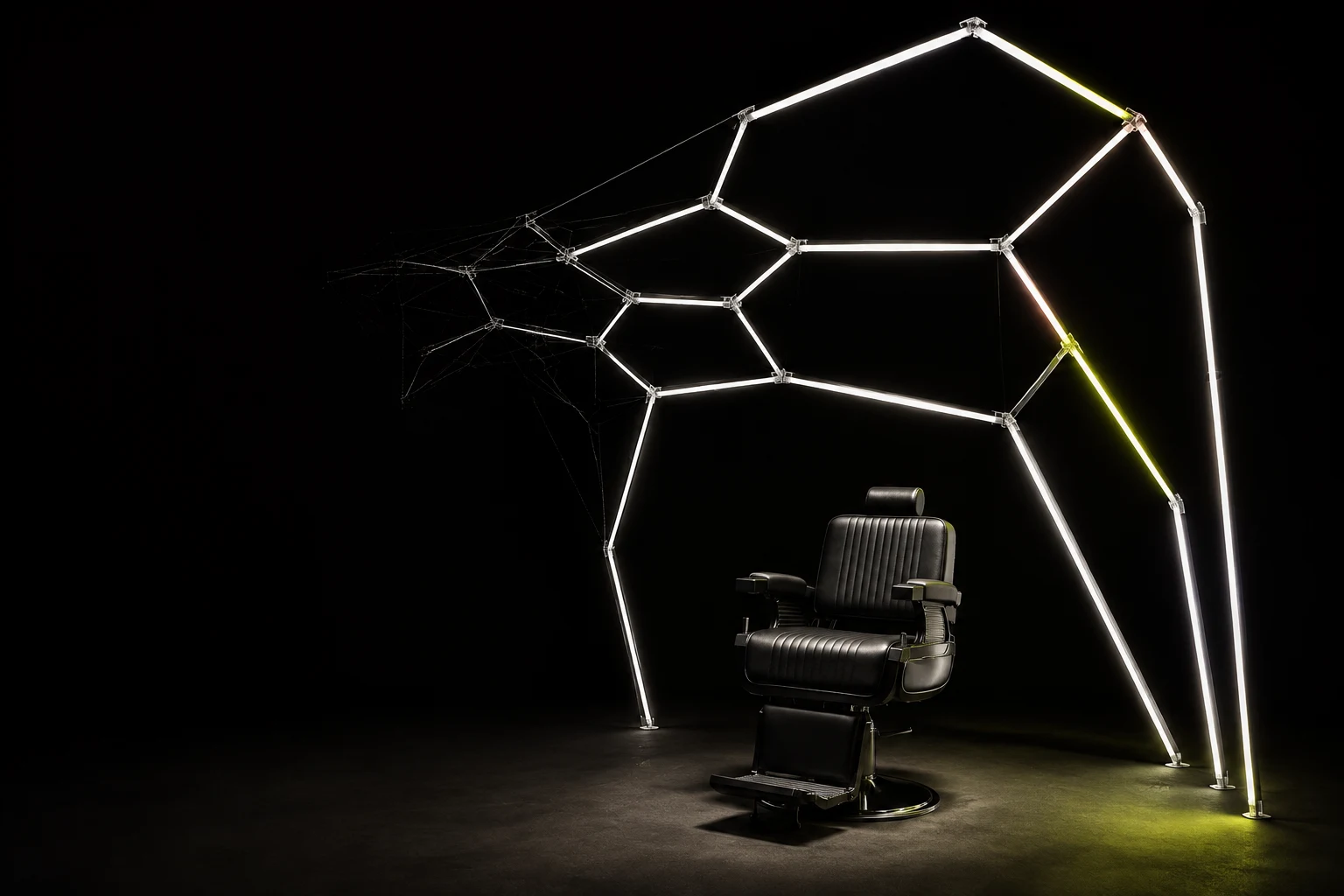 A barber chair beneath sculptural geometric lights in a dark studio